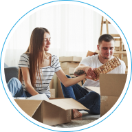 Pareja joven en el suelo desempacando cajas, representando la gestión de arriendos y administración de propiedades de inversión.